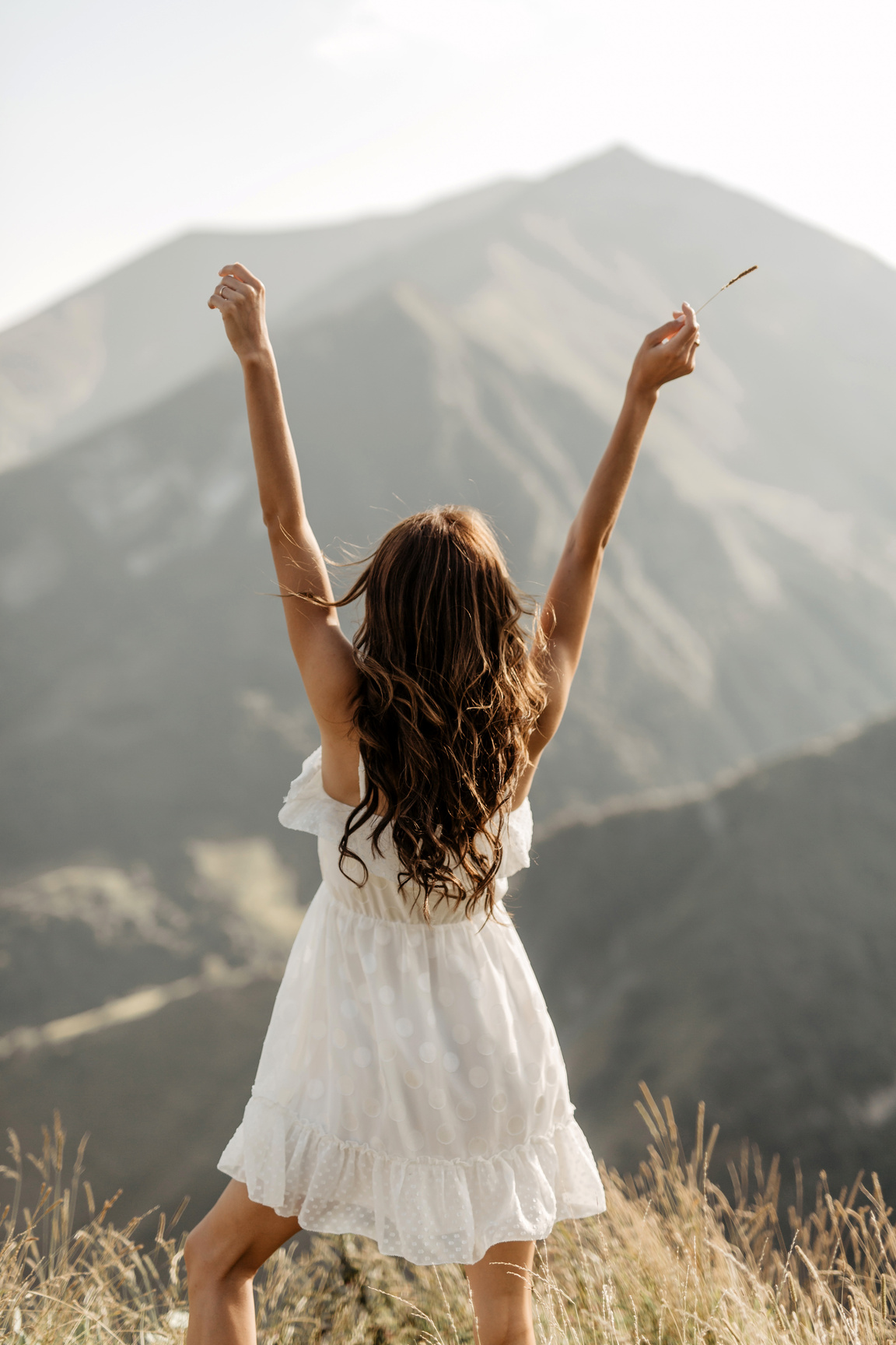 Back View of a Carefree Woman in White Dress Raising Her Both Arms